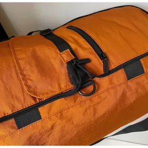 Close-up of smooth black zipper and nylon fabric on orange travel duffle bag