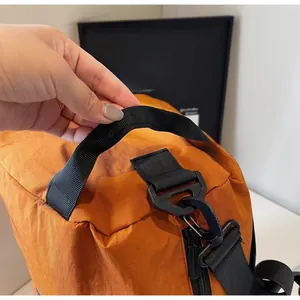 Detail of durable orange nylon travel bag showing reinforced black handles and plastic hook