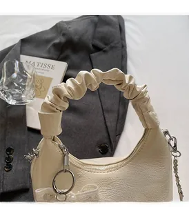 Detail der beigen Kunstledertasche mit Falten Griff und eleganter Spitzen Perlen Schleife