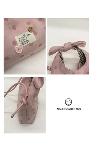 Détail du sac rose à pois avec étiquette chat, bouton en bois et doublure rayée