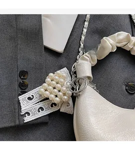 Detailansicht der cremefarbenen Lackledertasche mit gerafftem Griff und Herz-Charm