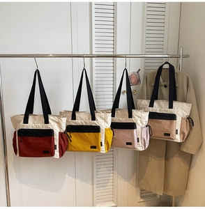 Detail view of large capacity contrast tote bags in four colors hanging on a rack