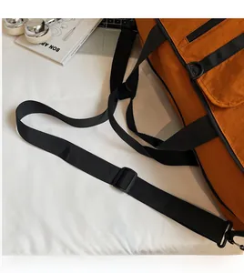Detail of adjustable black shoulder strap and D-ring on orange travel sports bag