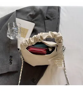 Innenansicht der cremefarbenen Faltenhandtasche mit Platz für Geldbörse und Perlenanhänger