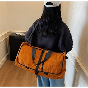 Close-up of orange waterproof nylon duffle bag with black straps and side zipper