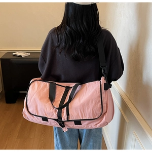 Detail of pink waterproof travel bag with reinforced black handles and adjustable shoulder strap