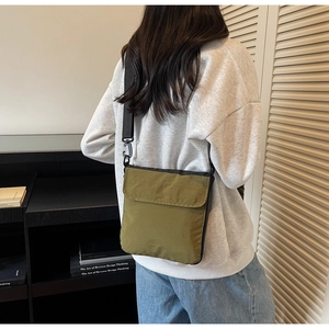 Outdoor detail of olive green nylon crossbody bag with adjustable strap and flap closure