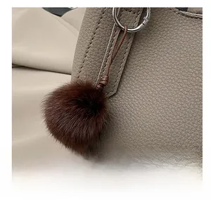 Détail d'un bijou de sac en fourrure marron foncé avec des perles rétro sur un sac gris