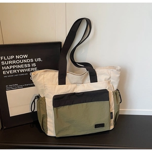 Close-up of color-block nylon tote bag showing olive green pocket and drawstring detail
