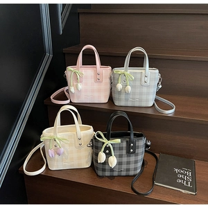 Détail de quatre sacs seaux à carreaux en rose, gris, beige et noir avec charms tulipes