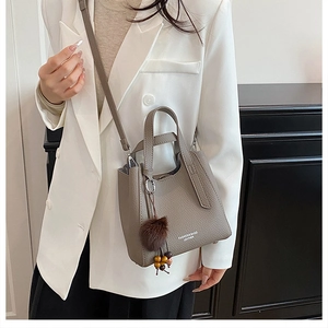 Détail d'un sac seau en cuir grainé terre cuite avec pompon et breloque perlée