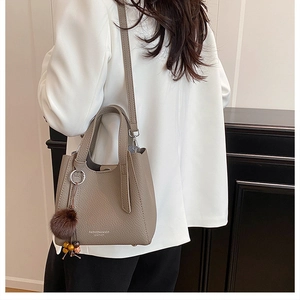Mannequin portant un sac bandoulière taupe en cuir avec pompon et perles chic