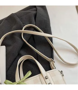 Détails de la bandoulière réglable et du motif en damier sur le sac seau crème