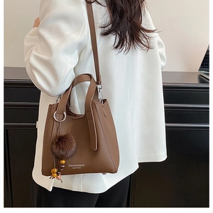 Détail du sac en cuir marron motif litchi avec pompon et breloque en perles de bois