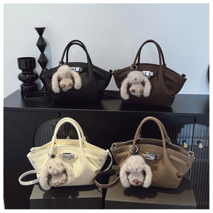 Detail view of four textured leather bucket bags in different colors with bunny charms