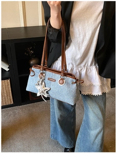 Dettaglio di borsa bowling in denim con cinturini in pelle marrone e ciondolo a stella