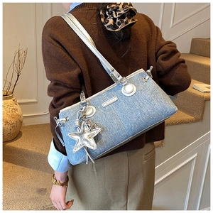 Dettaglio borsa bowling in denim con manici argento e ciondolo a stella con paillettes