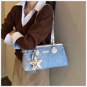 Dettaglio della borsa a spalla in denim azzurro con bordo argento e ciondolo stella