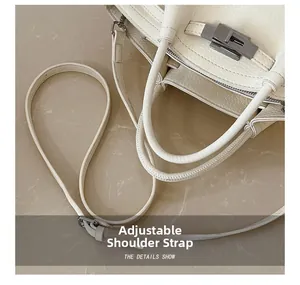 Detail view of cream pebble leather bag showing silver twist lock and adjustable strap