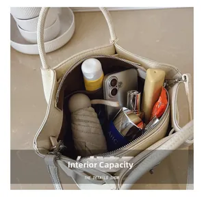 Spacious interior of a beige leather bucket bag showing capacity for daily essentials