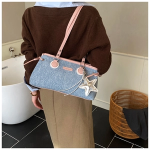 Dettaglio della borsa a spalla in denim con finiture in pelle rosa e ciondolo a stella