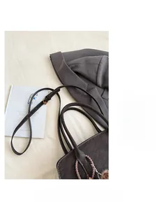 Détail d'un grand sac cabas vintage en cuir marron avec pendentif perlé et pompon en fourrure