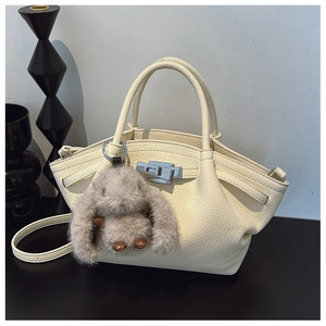 Detail of cream white pebbled leather handbag featuring silver hardware and plush bunny charm