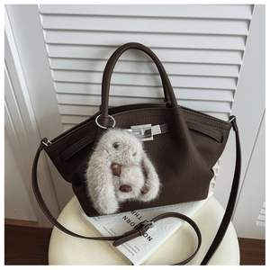 Close-up of dark brown lychee grain leather tote with silver lock and plush bunny charm