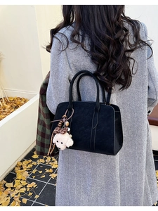 Détail d'un sac cabas noir vintage avec breloque chiot en peluche et nœud léopard