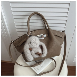 Close-up of brown pebbled leather bucket bag with silver twist lock and bunny charm