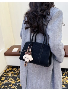 Détail d'un sac cabas noir orné d'un joli pendentif en peluche en forme de chiot blanc