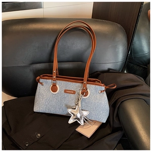 Dettaglio della borsa a spalla in denim con finiture in pelle marrone e ciondolo a stella