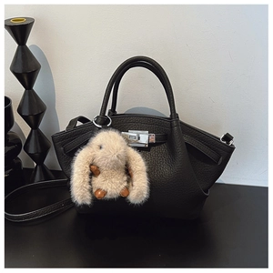 Detail of black lychee grain leather bucket bag with silver twist lock and bunny charm