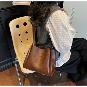 Detailansicht der braunen Vintage-Leder-Einkaufstasche mit Logo und feiner Texturierung