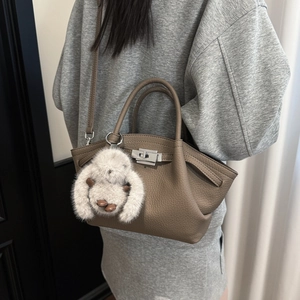 Detail view of taupe lindy style bag featuring lychee grain leather and plush bunny charm