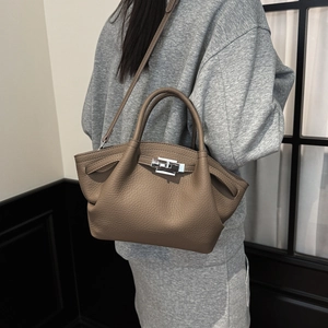 Close-up of brown lychee grain leather bucket bag featuring a polished metal swivel lock