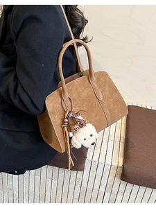 Détail du sac cabas en daim marron avec un charme chien teddy blanc et un gland tissé