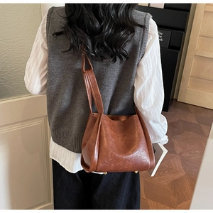 Nahaufnahme der braunen Vintage-Tasche mit goldenen Bodennägeln und strukturierter Textur