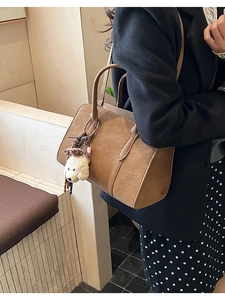Sac fourre-tout en daim marron avec pendentif chiot peluche porté par un mannequin élégant