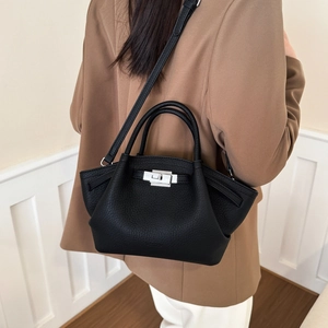 Black lychee leather crossbody bag with silver lock worn by model in brown blazer