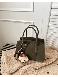 Détail du sac cabas vert foncé en cuir suédé mat avec un joli pendentif chien en peluche
