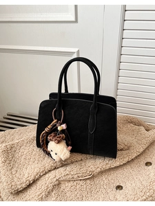 Détail du sac cabas en similicuir noir avec un charmant ours en peluche sur une veste