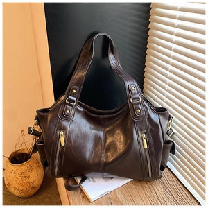 Close-up of deep brown oil wax leather tote with golden buckles and vintage texture