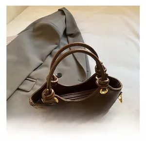 Close-up of retro brown bucket bag with knotted handle and decorative colorful beads