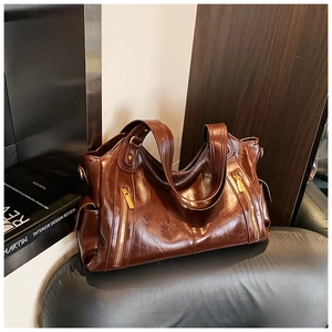 Detail of dark brown vintage oil wax leather bag with double zippers and gold hardware