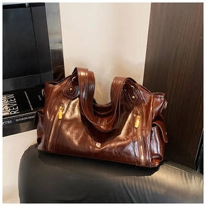 Detail of vintage dark brown tote bag with glossy leather finish and dual golden zippers
