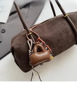 Close-up of brown faux leather mini bag charm with hand-stitched detail on suede tote