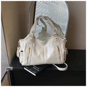 Detail view of cream white tote bag with vertical zipper pockets and golden hardware