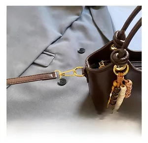 Detail of dark brown leather bucket bag with gold hook and beaded fringe tassel