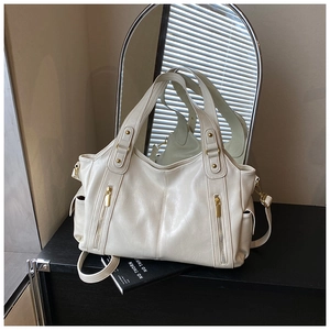 Detail view of cream tote bag with dual gold zippers and reinforced rivet handles